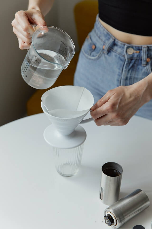 A woman pouring coffee into a glass.