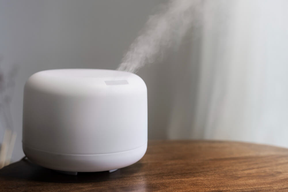 A white humidifier sitting on a wooden table.