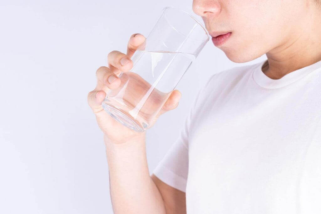 Person in a white shirt drinking a glass of water.