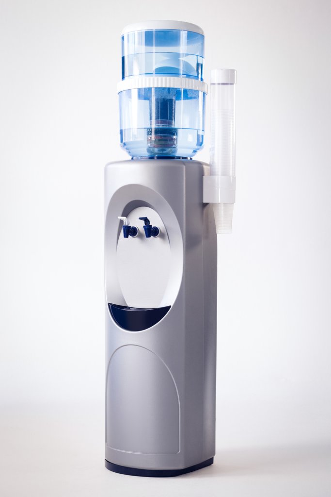 A gray water cooler with a large blue water jug on top and a stack of clear plastic cups on the side, set against a plain white background—ideal for those comparing water dispenser Singapore price options.