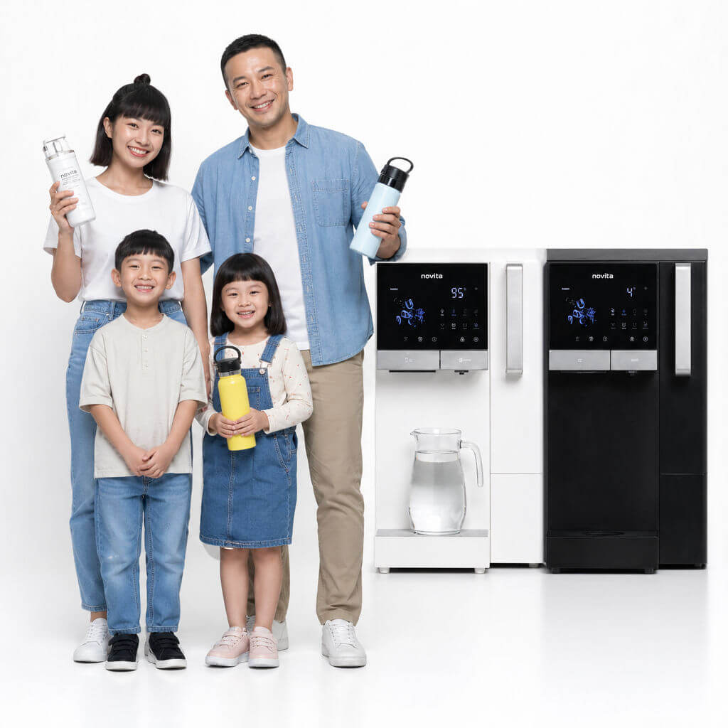 A family of four stands smiling with water bottles in front of two water coolers, one white and one black, against a plain white background.